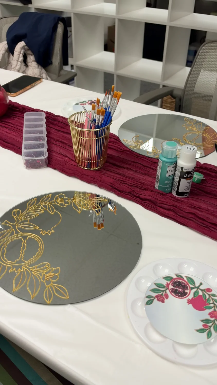 Prepared mirror outlines and paints at the workshop table